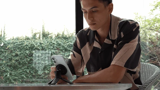 三脚でスマホを立てて見る男性