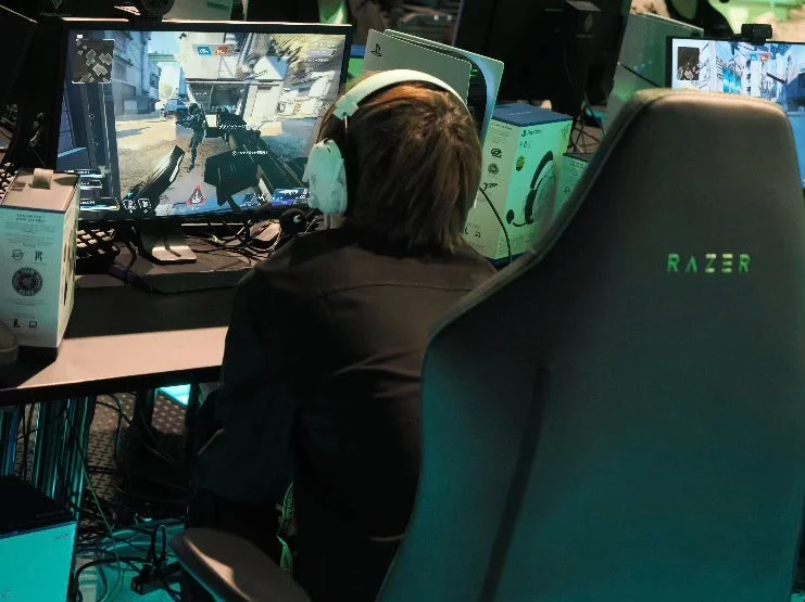 ゲーミングチェアに座りゲームをプレイする人物の背中