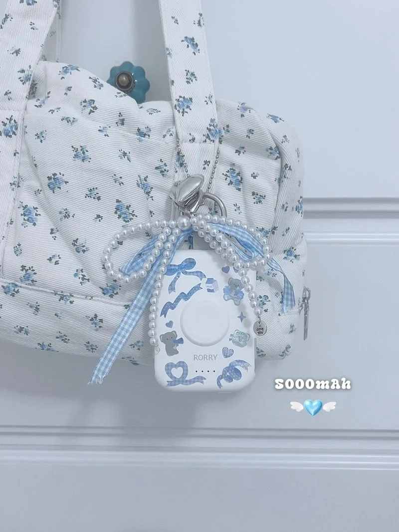 水色の花柄バッグに吊るされた、可愛らしいデコレーションのモバイルバッテリー