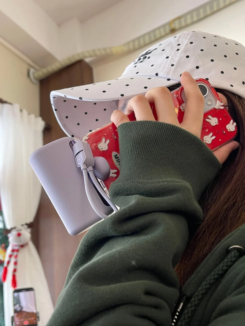 ミッフィーのスマホケースを持つ女性とモバイルバッテリー