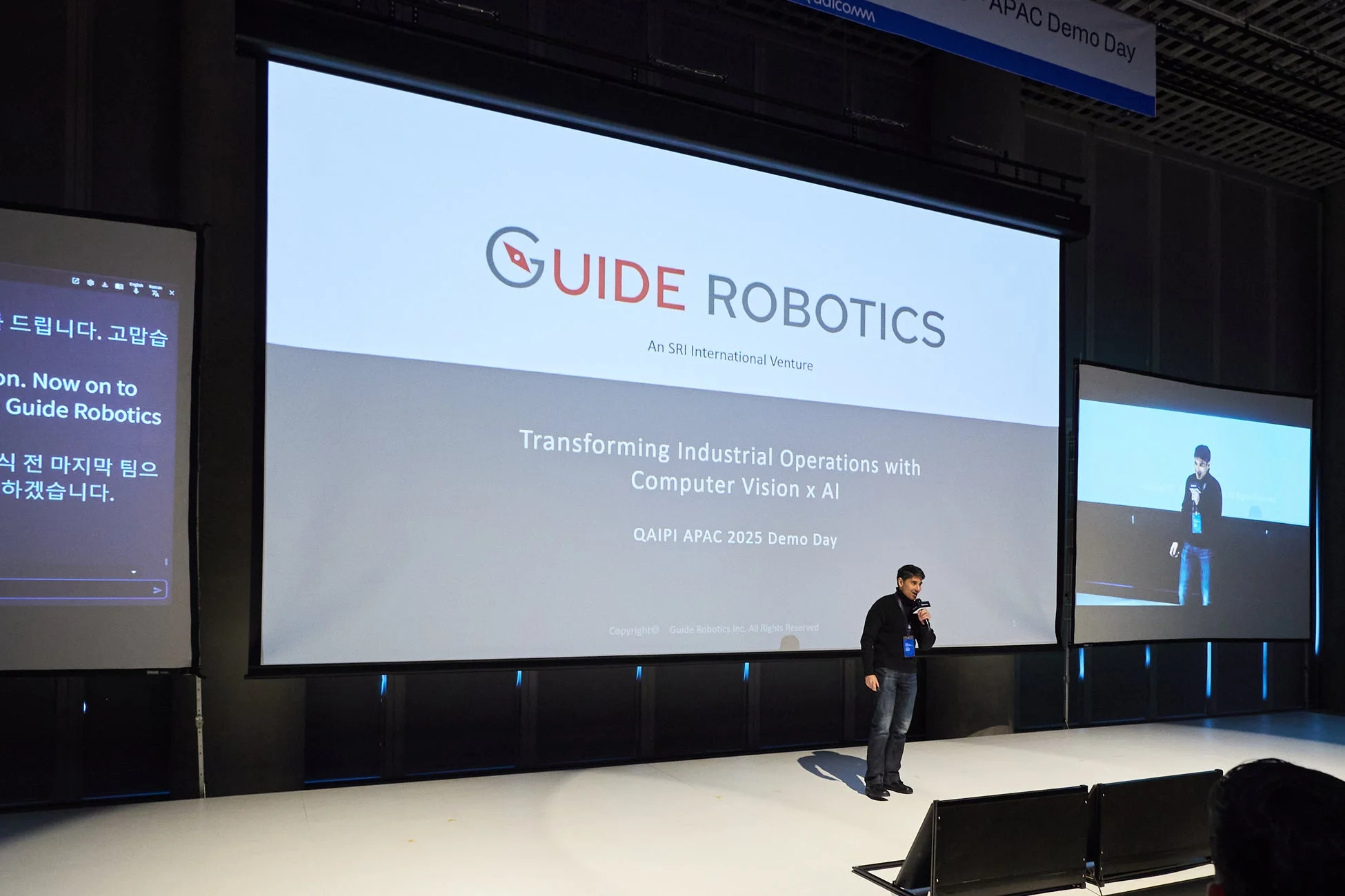 QAIPI APAC 2025 Demo Dayで、男性が「GUIDE ROBOTICS」についてプレゼンテーションを行っています。