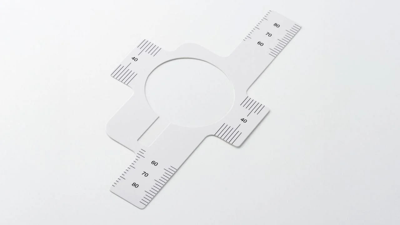 白い背景に、中央に円形の切り抜きがある白い特殊な定規が置かれています。定規には「40」「60」「70」「80」といった数字と目盛りが印字されており、測定用途の道具であることがわかります。