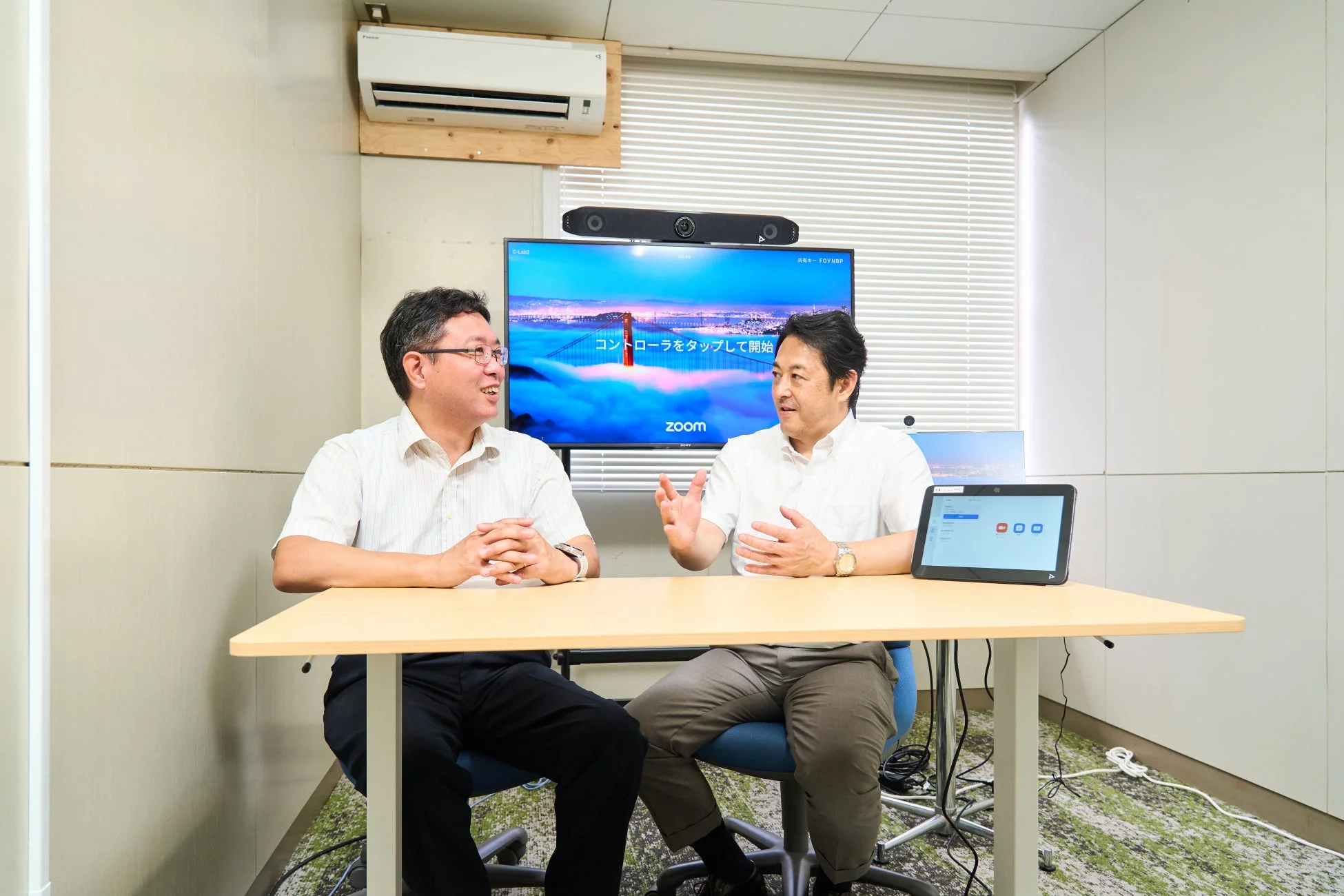 オフィスで2人の男性がテーブルを挟んで会話