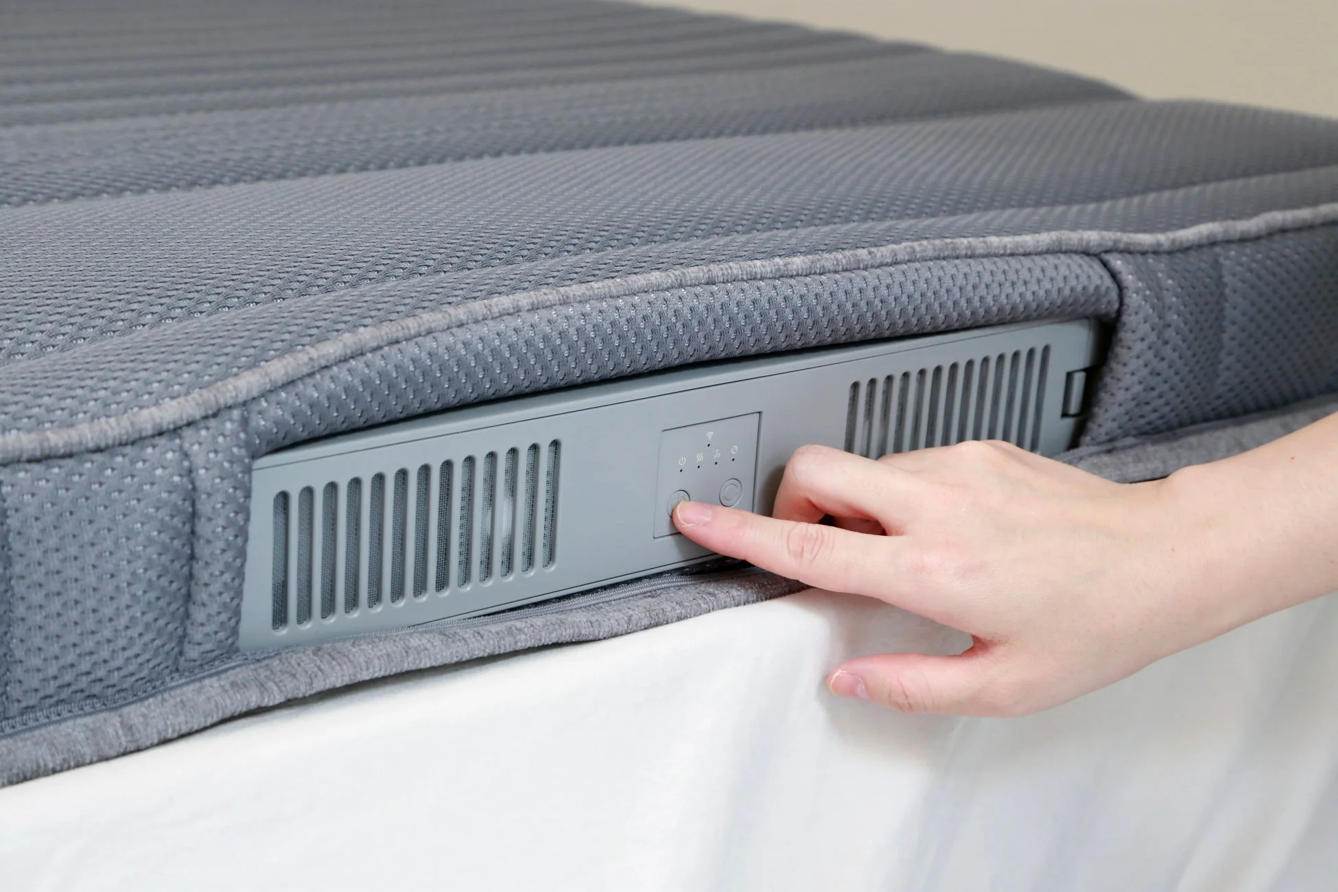 マットレスに内蔵された操作パネルを操作する手