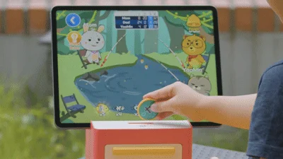 子供がタブレットの釣りゲームと連動する知育玩具で遊んでいる様子です。
