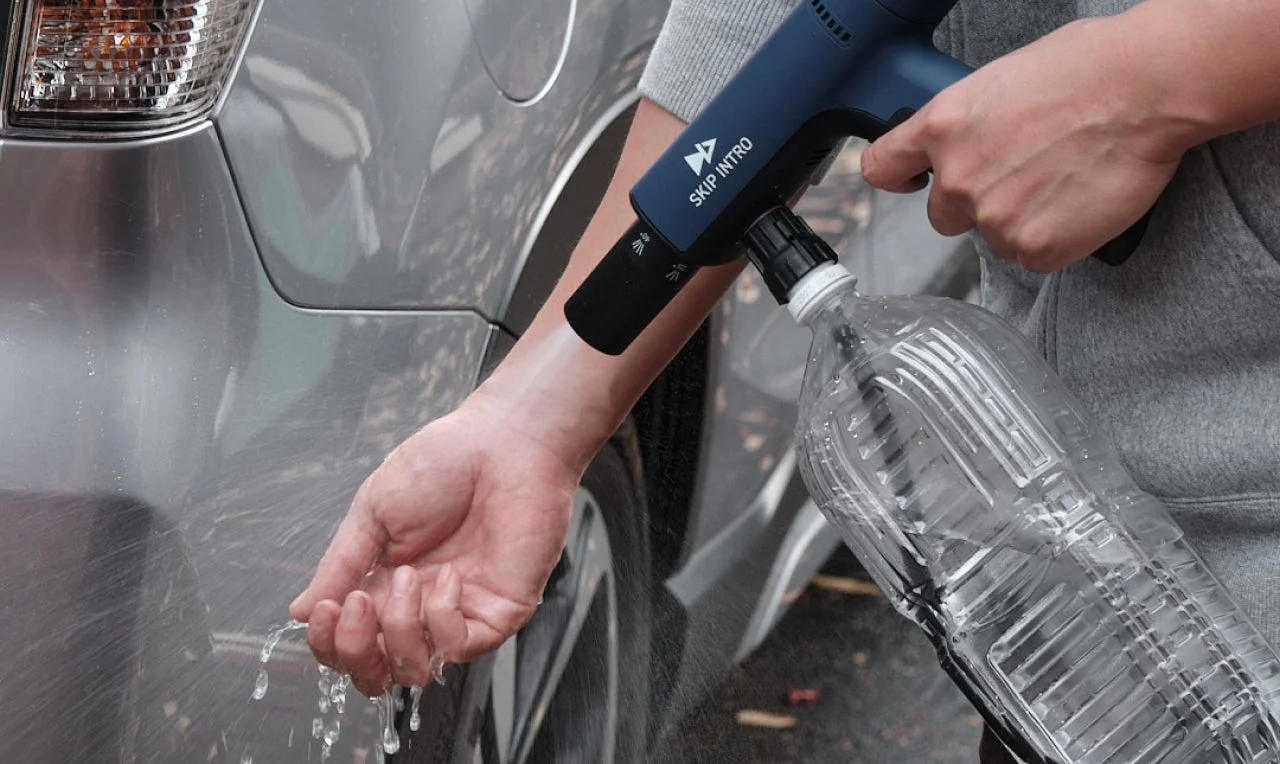 ペットボトルに取り付けられたポータブルスプレーで車に水をかけている様子