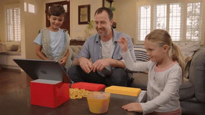 リビングルームで父親と2人の子供がタブレットを使ったインタラクティブなゲームを楽しんでいます。