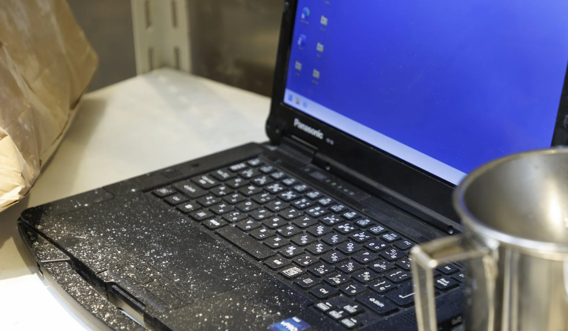 粉が付着したノートパソコンと作業環境
