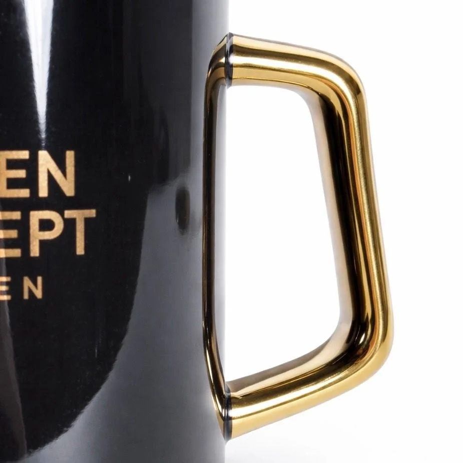 黒いマグカップの側面と、光沢のある金色の取っ手をクローズアップした画像です。
