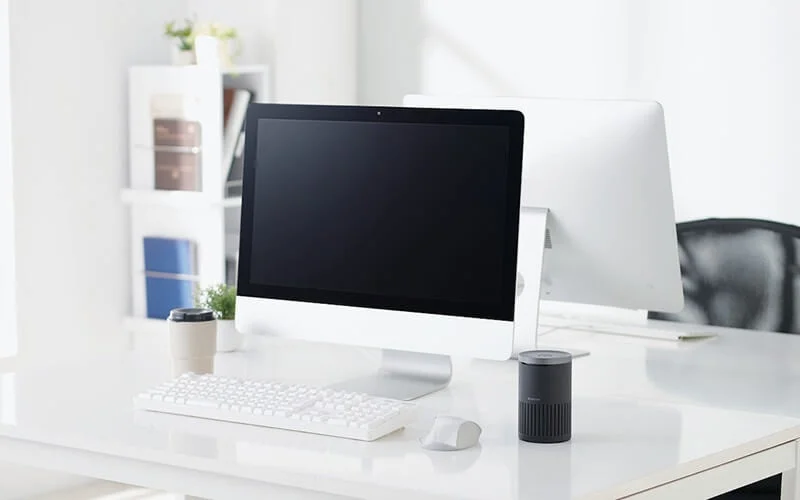 白いデスクに置かれたスピーカーフォンとモニター