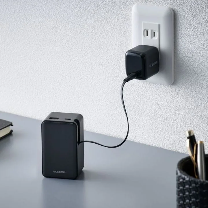 壁のコンセントに接続された充電器とデスク上のデバイス