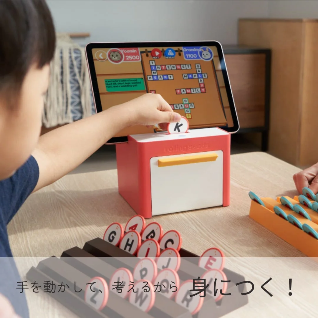 子供がタブレット連動型の知育玩具で、アルファベットのコマを使い英単語を学んでいる。