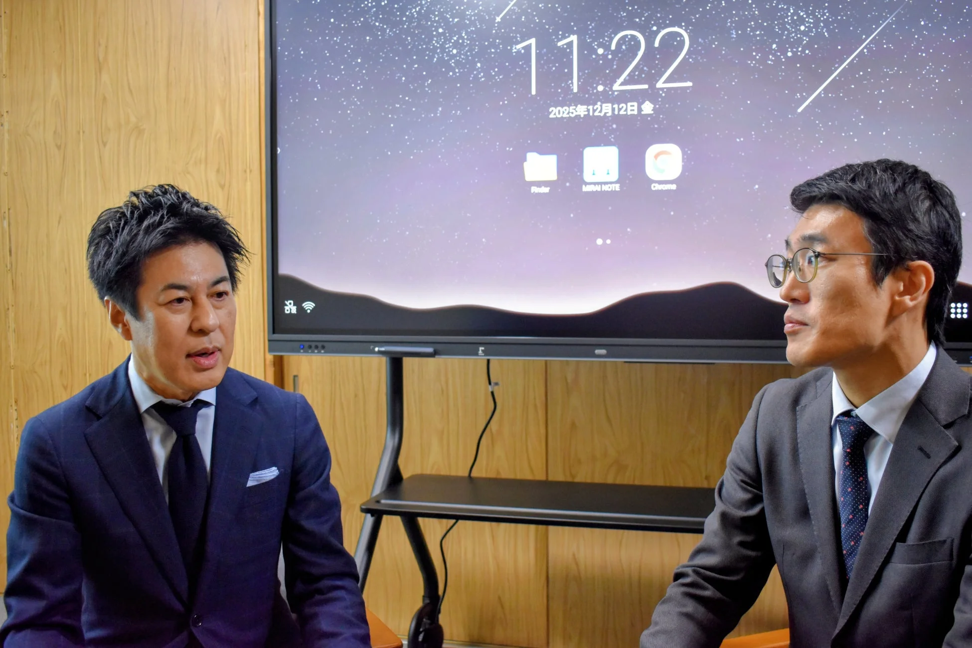 スーツを着た二人の男性が会議室のような場所で話しています