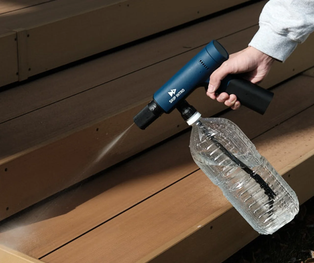 ペットボトルに取り付けられたポータブルウォッシャーが水を噴射する様子