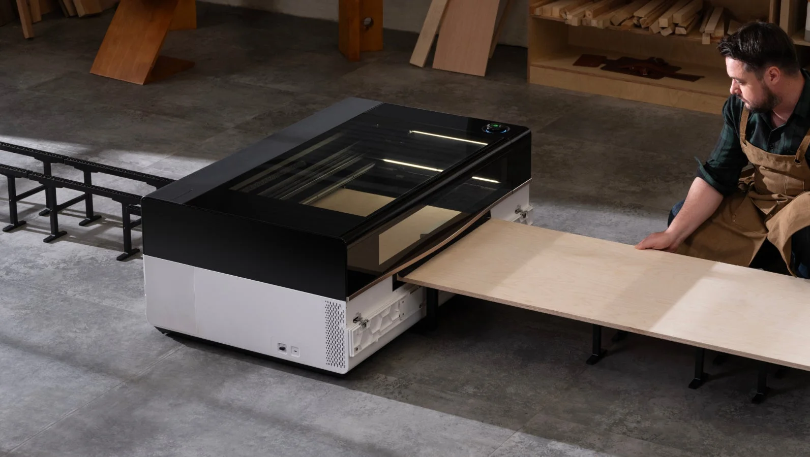 ワークショップで、男性が大型の木材を最新のレーザー加工機にセットしている様子