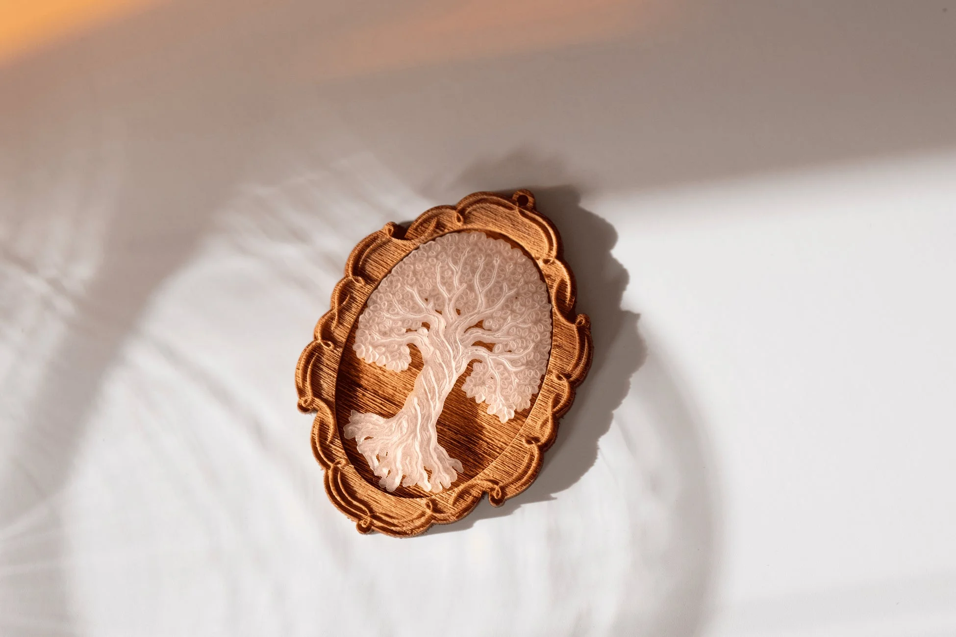 白い背景に置かれた、生命の樹をモチーフにした半透明の彫刻が美しい木製フレームのオブジェ