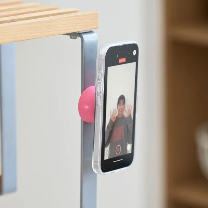 マグネットで棚に固定されたスマホで撮影する女性