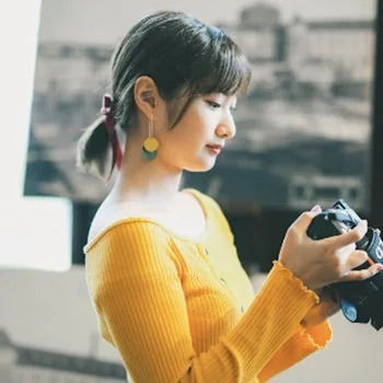 黄色いトップスを着てカメラの液晶画面を覗き込むNatsuka