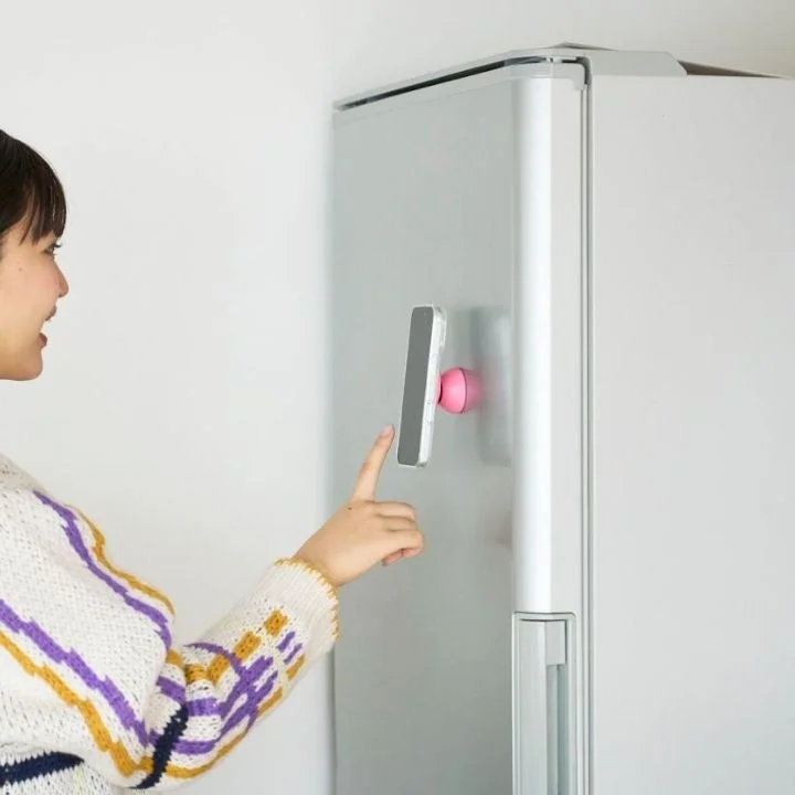 冷蔵庫に固定されたスマホでレシピを見る女性