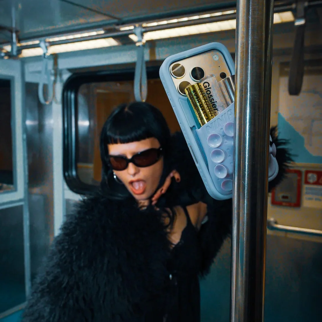 地下鉄内でスマホを固定してメイクする女性