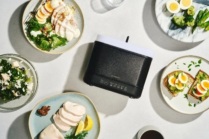 卵料理、サラダ、鶏肉などのヘルシーな食事が彩り豊かに並び、中央には調理家電が置かれています。