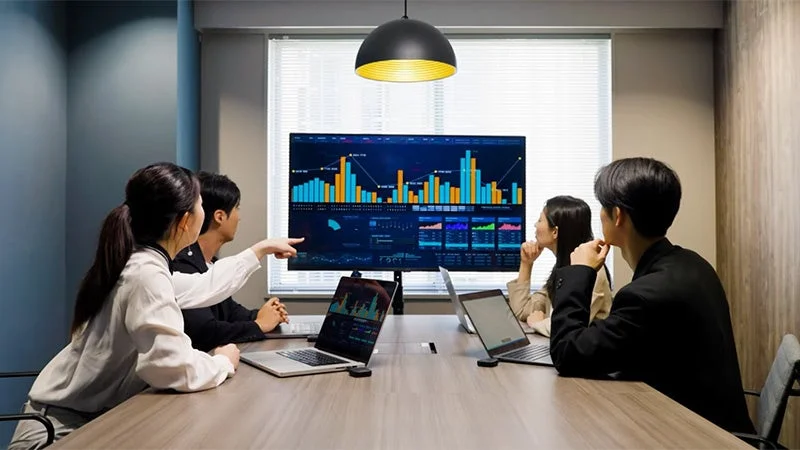 会議室でデータ分析のグラフを見ている人々