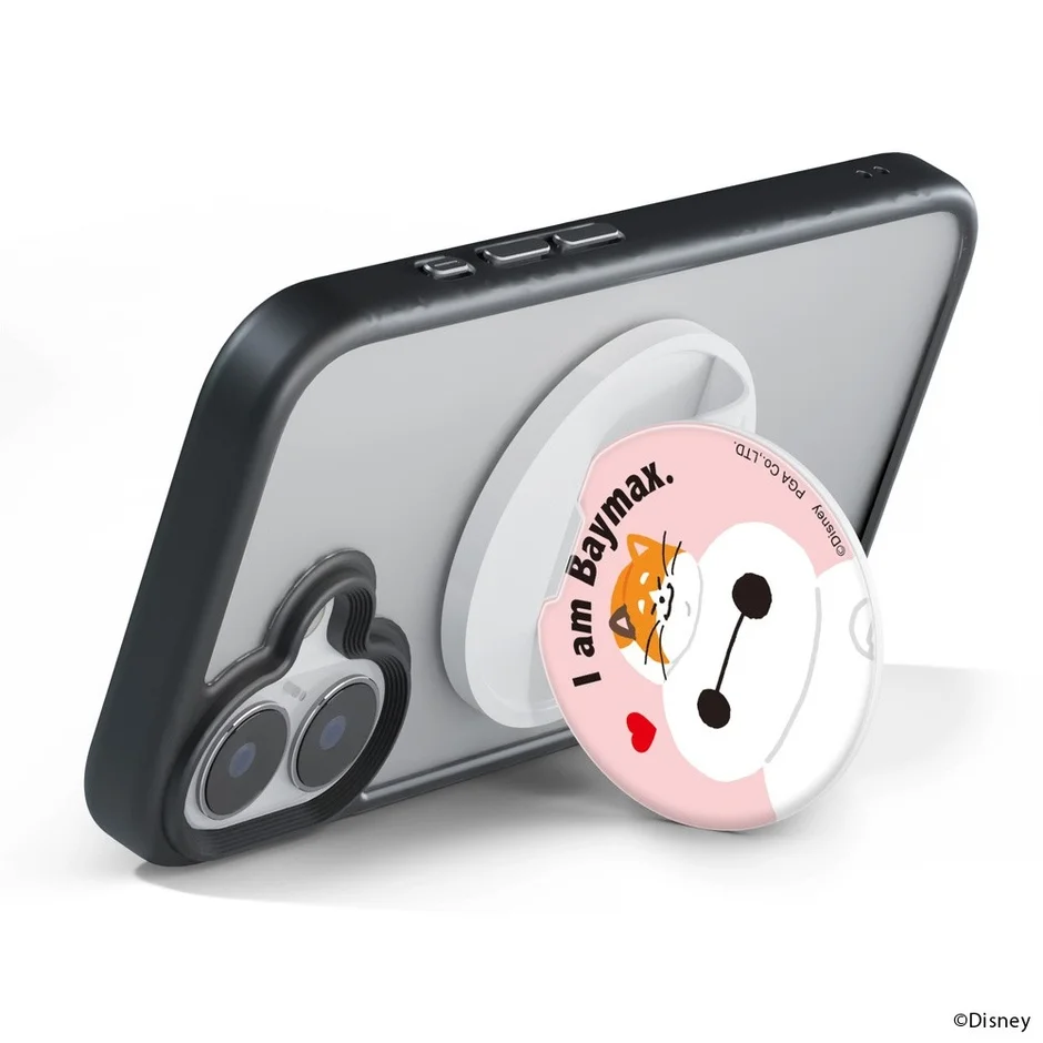 透明なスマホケース付きスマートフォンに、ベイマックスと柴犬が描かれたピンクのスマホリングが装着されています。