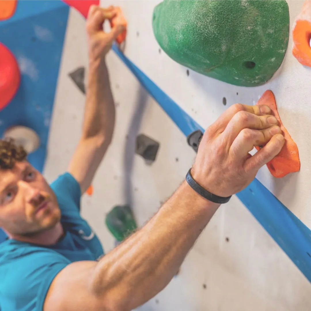 ボルダリングウォールを登る男性