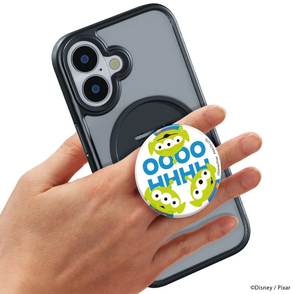 透明なスマホケースを装着したiPhoneを手に持っており、背面にはトイ・ストーリーのリトルグリーンメンがデザインされた円形のスマホリングが取り付けられています。
