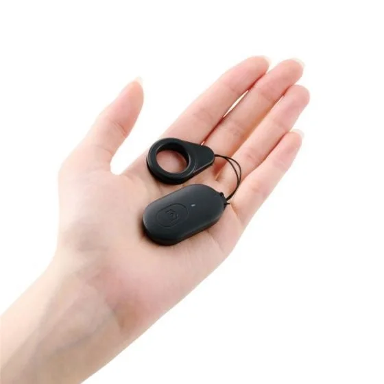 白い背景に手のひらに乗せられた小型の黒いワイヤレスシャッターリモコンの画像です。中央にカメラアイコンがあり、ストラップとリングが付属しています。