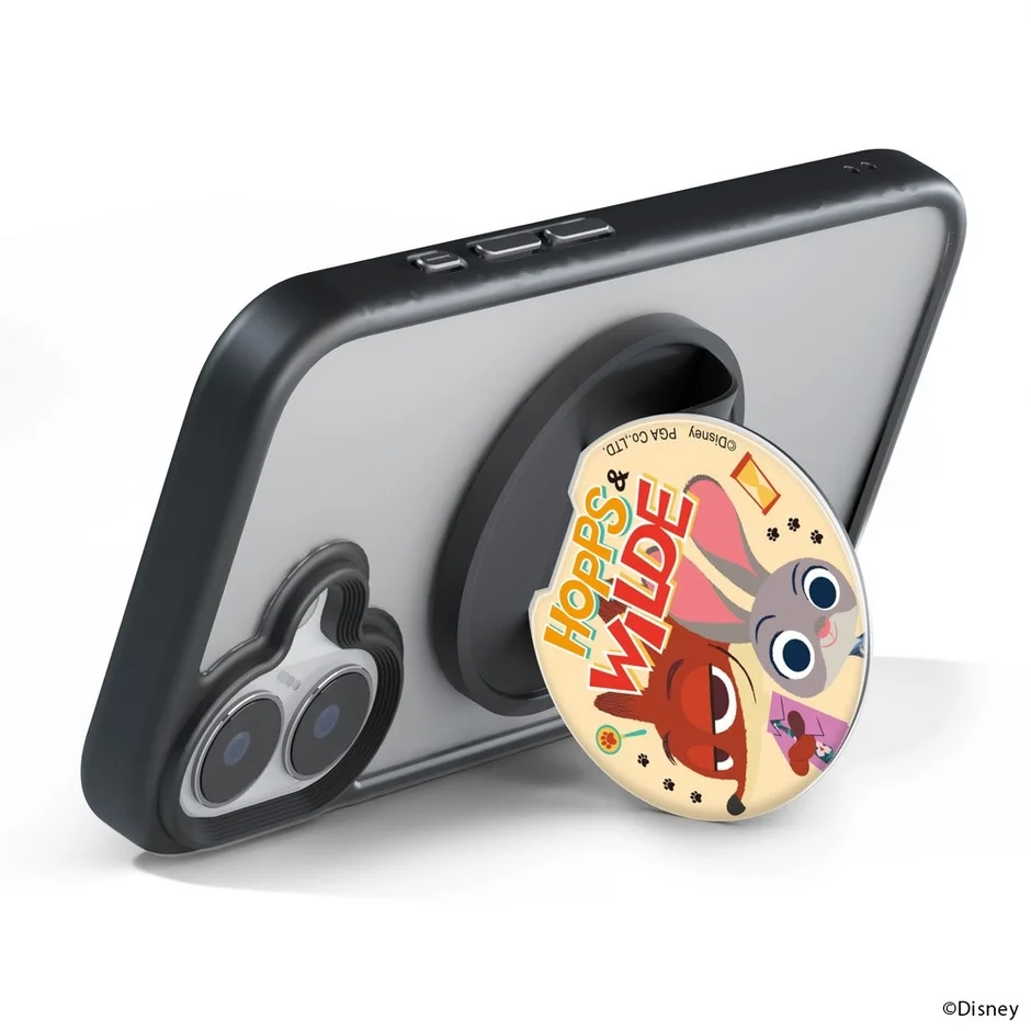 スマートフォンに装着された「ズートピア」のジュディとニックが描かれたポップソケット型スマホスタンドが、本体を支えている様子を捉えた画像です。
