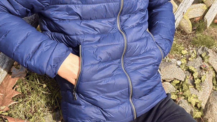 青いダウンジャケットを着た人物がポケットに手を入れている