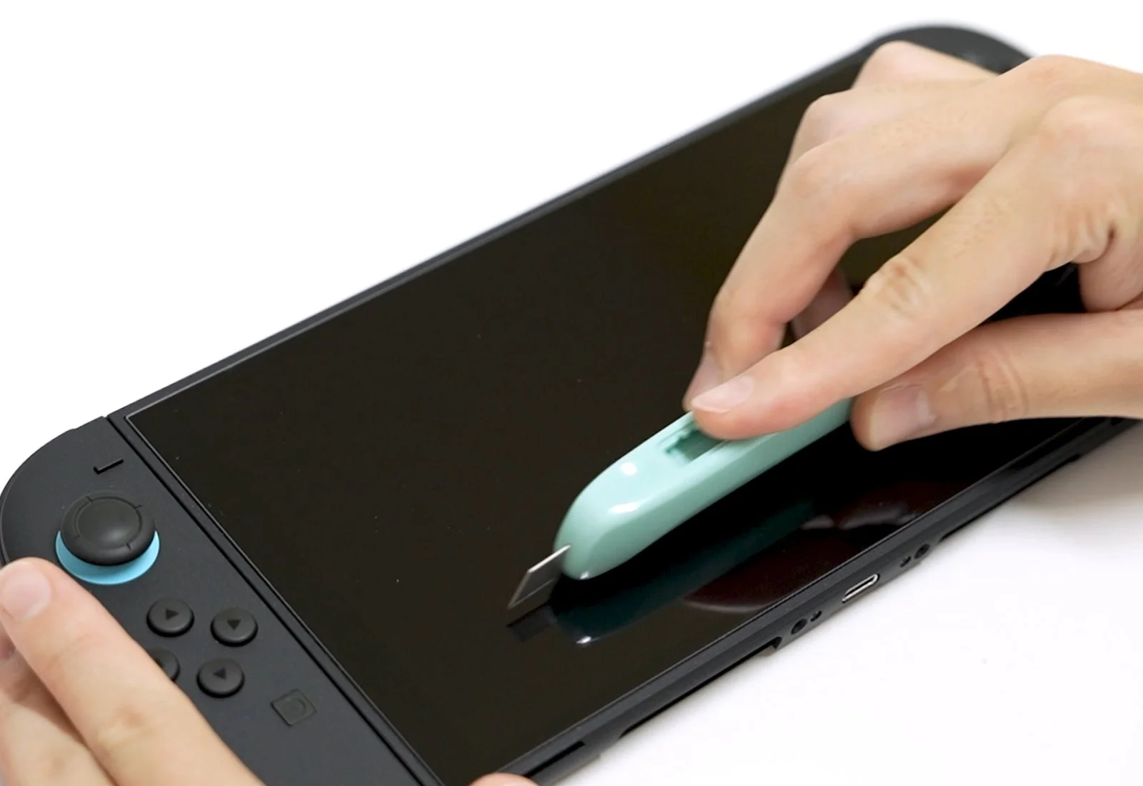 携帯ゲーム機の画面にカッターナイフ