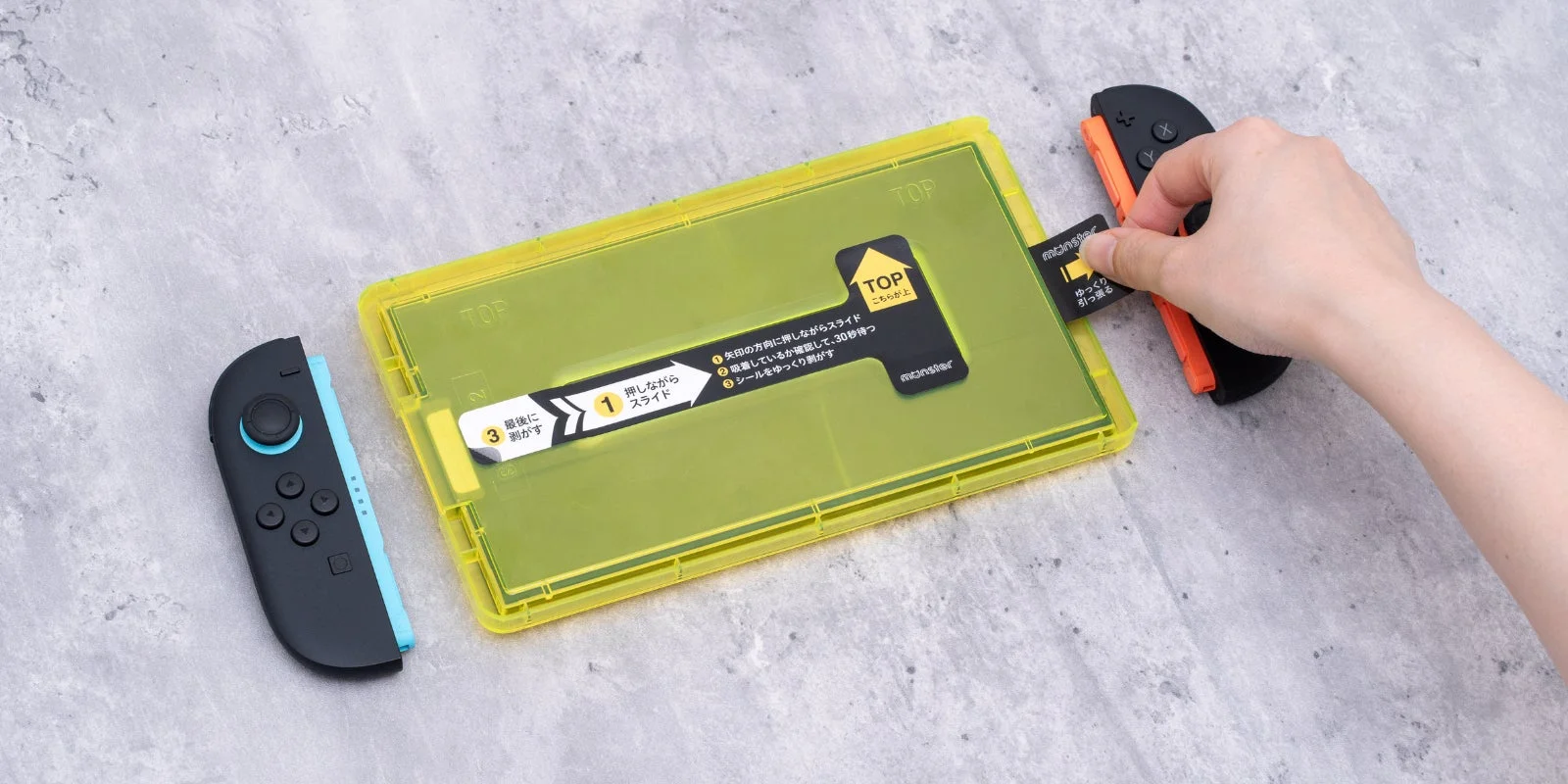 Nintendo Switchの画面に液晶保護フィルムを貼り付けている様子
