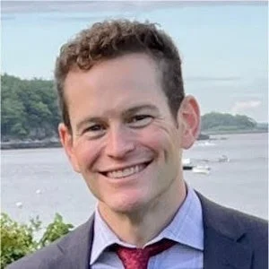 スーツとネクタイを着用した男性が屋外で笑顔を見せているポートレート