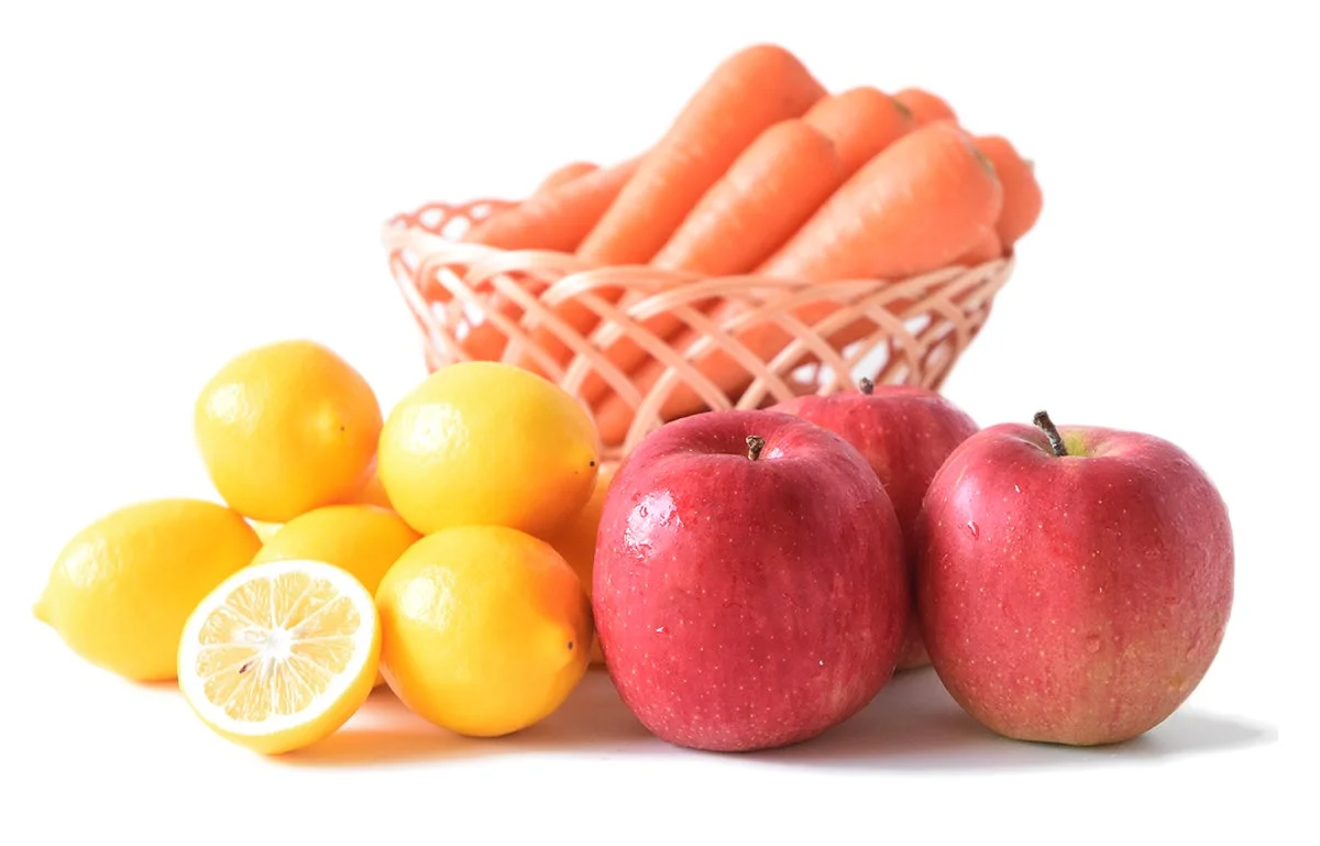 かごに入った新鮮なにんじんと、レモンとりんご