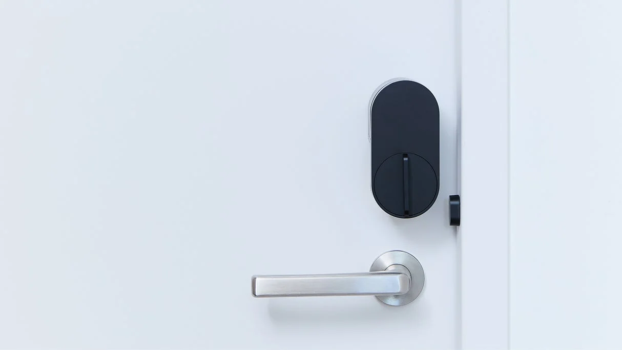 白いドアに設置されたシルバーのドアハンドルと黒いスマートロックデバイス