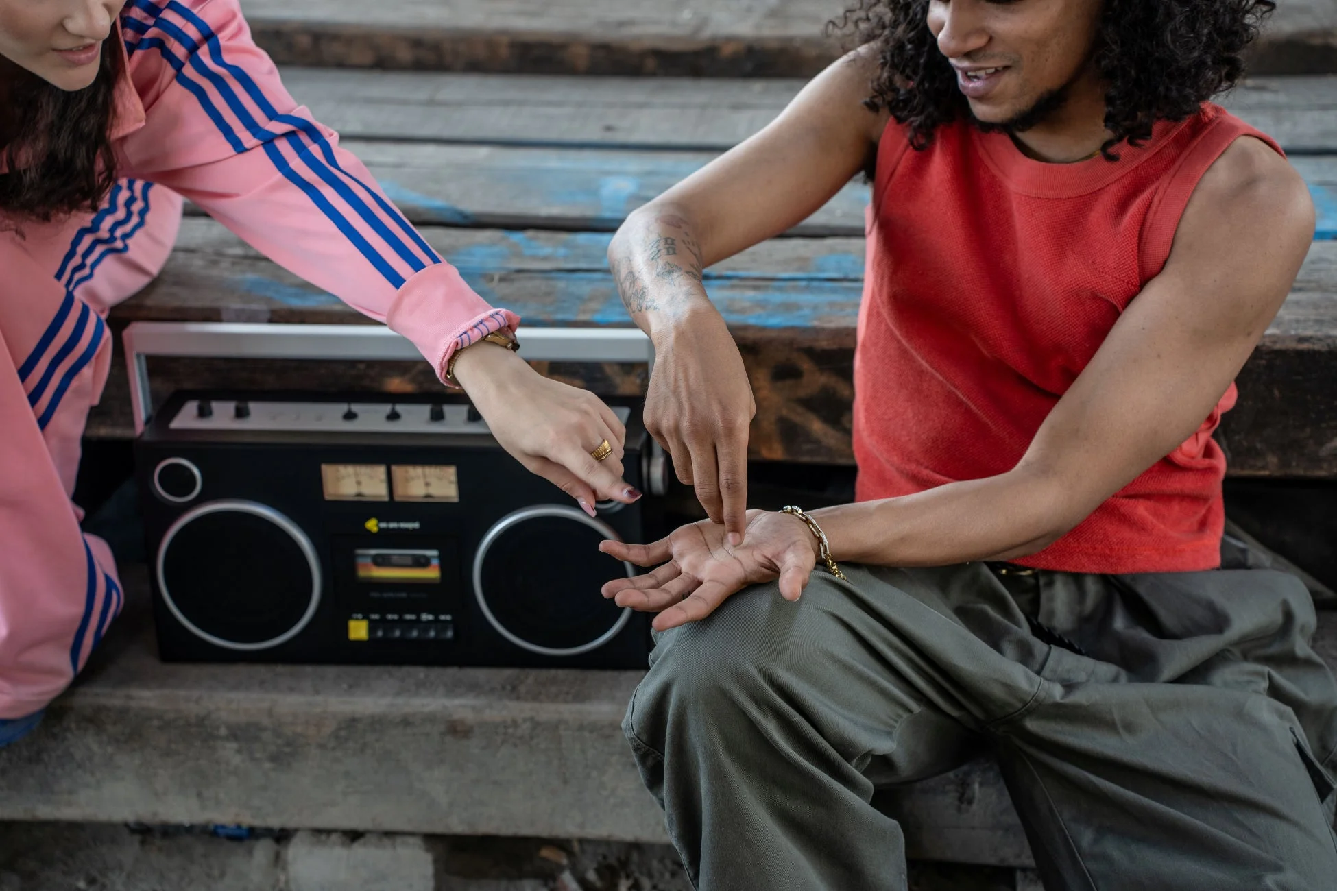 レトロなブームボックスのそばで、男女が親密に手を重ねる