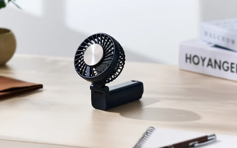 木製のデスクに置かれた黒い携帯扇風機