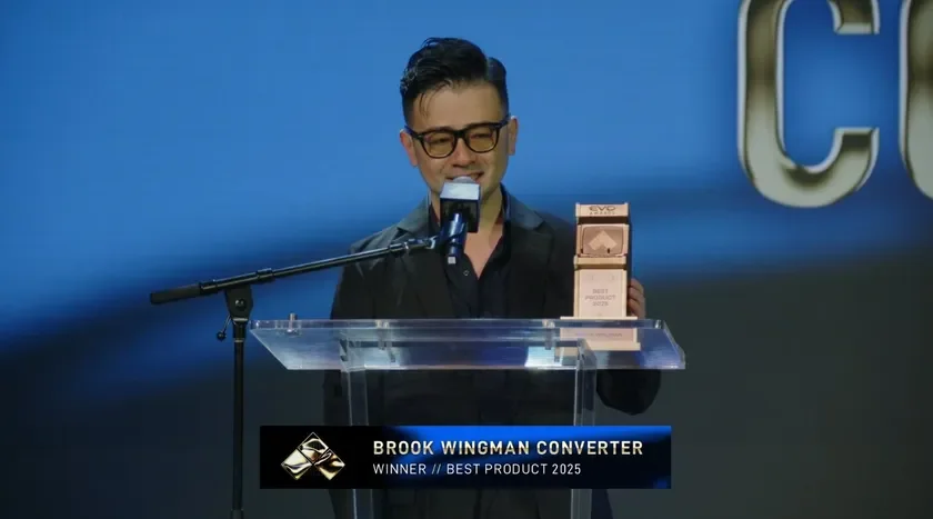 EVOアワードの授賞式で、一人の男性が「BEST PRODUCT 2025」を受賞した「BROOK WINGMAN CONVERTER」のトロフィーを持ち、スピーチをしている様子です。