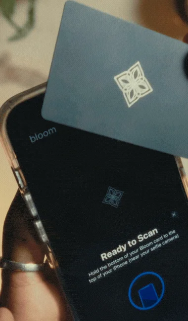 スマートフォンアプリ「bloom」を使って、専用のカードをスマートフォンの上部に近づけてスキャンしている様子です。
