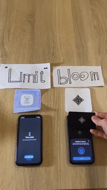 木製のテーブル上に2台のiPhoneが置かれ、片方にはTikTokの利用時間制限通知、もう片方にはBloom Walletのスキャン準備画面が表示されています。