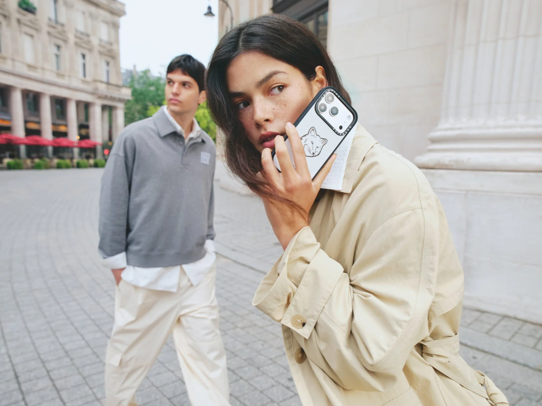 街中でスマートフォンを構える女性。キツネのデザインが施されたスマホケースが印象的です。