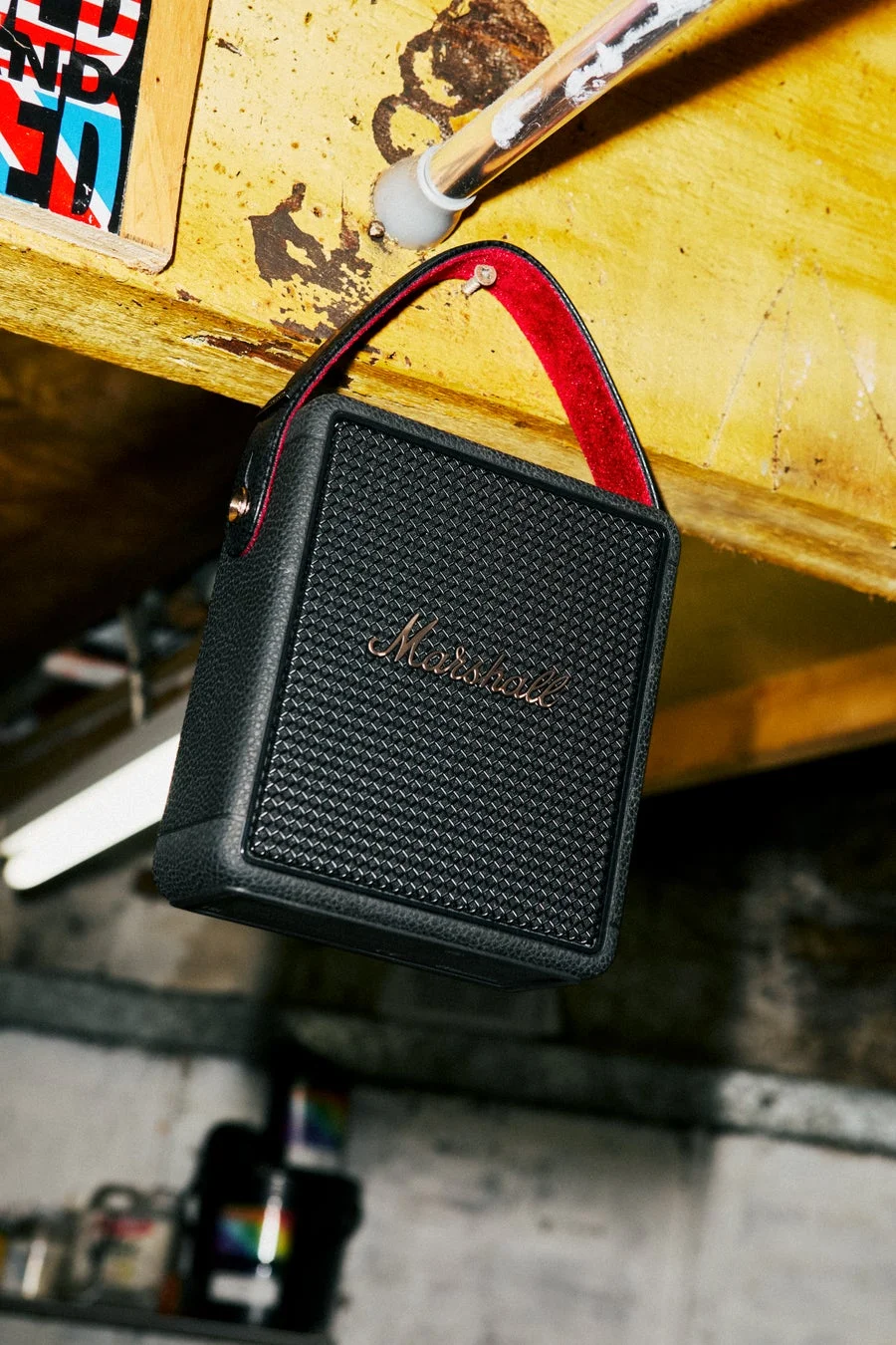 黒いMarshall製ポータブルスピーカーが、赤いストラップで木の梁から吊り下げられています