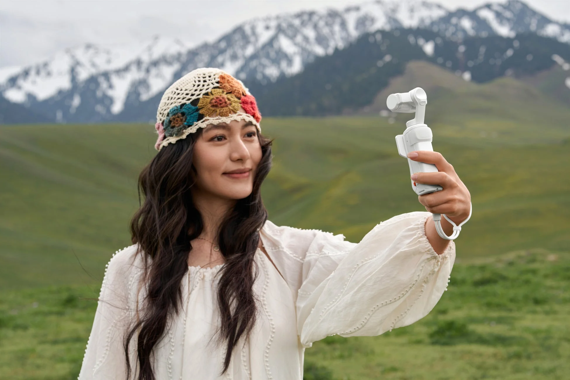 雪山と草原でカメラを持つ女性