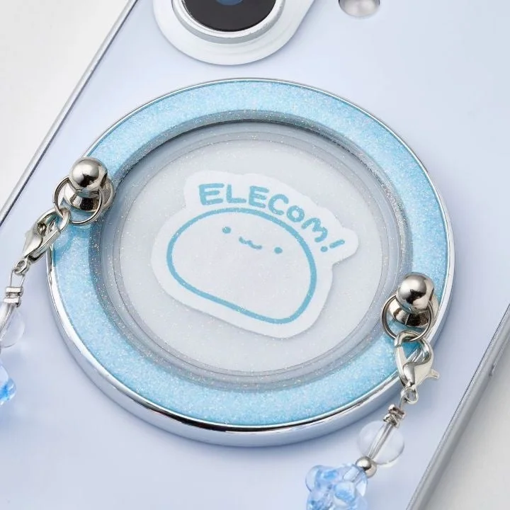 水色のグリッターが施されたスマートフォンアクセサリーのクローズアップ画像です。中央には「ELECOM!」の文字と可愛らしいキャラクターが描かれたシートが挟み込まれており、ストラップを取り付けるための金具も確認できます。