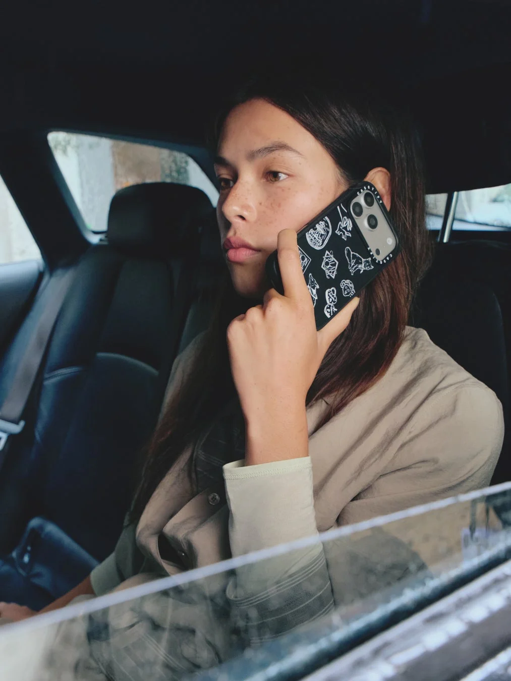 車内でスマートフォンを使って通話する女性。黒いCASETiFYのスマホケースを使用しています。